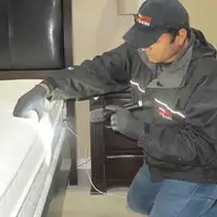 Bed bug inspection technician checking a mattress and bed frame for signs of infestation in Albany, NY