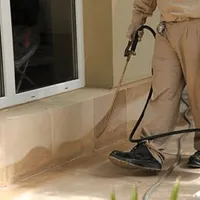 General pest control technician spraying exterior perimeter around a home in Albany, NY