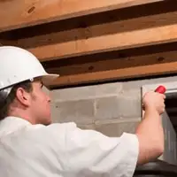 Termite inspection technician checking a basement wall and framing for termite activity in Albany, NY
